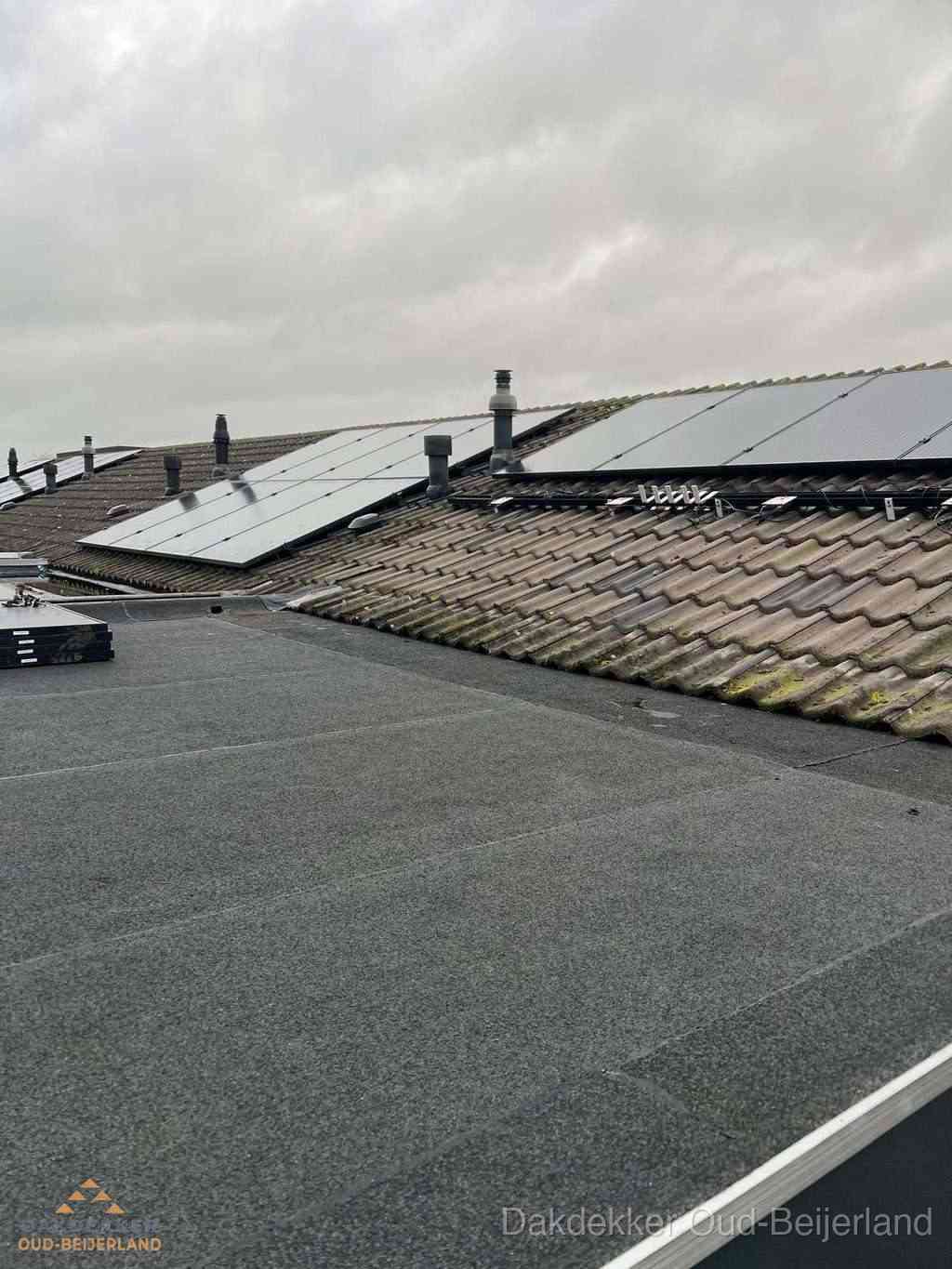 Plat dak inspectie met bitumen bedekking naast schuin pannendak in Oud-Beijerland